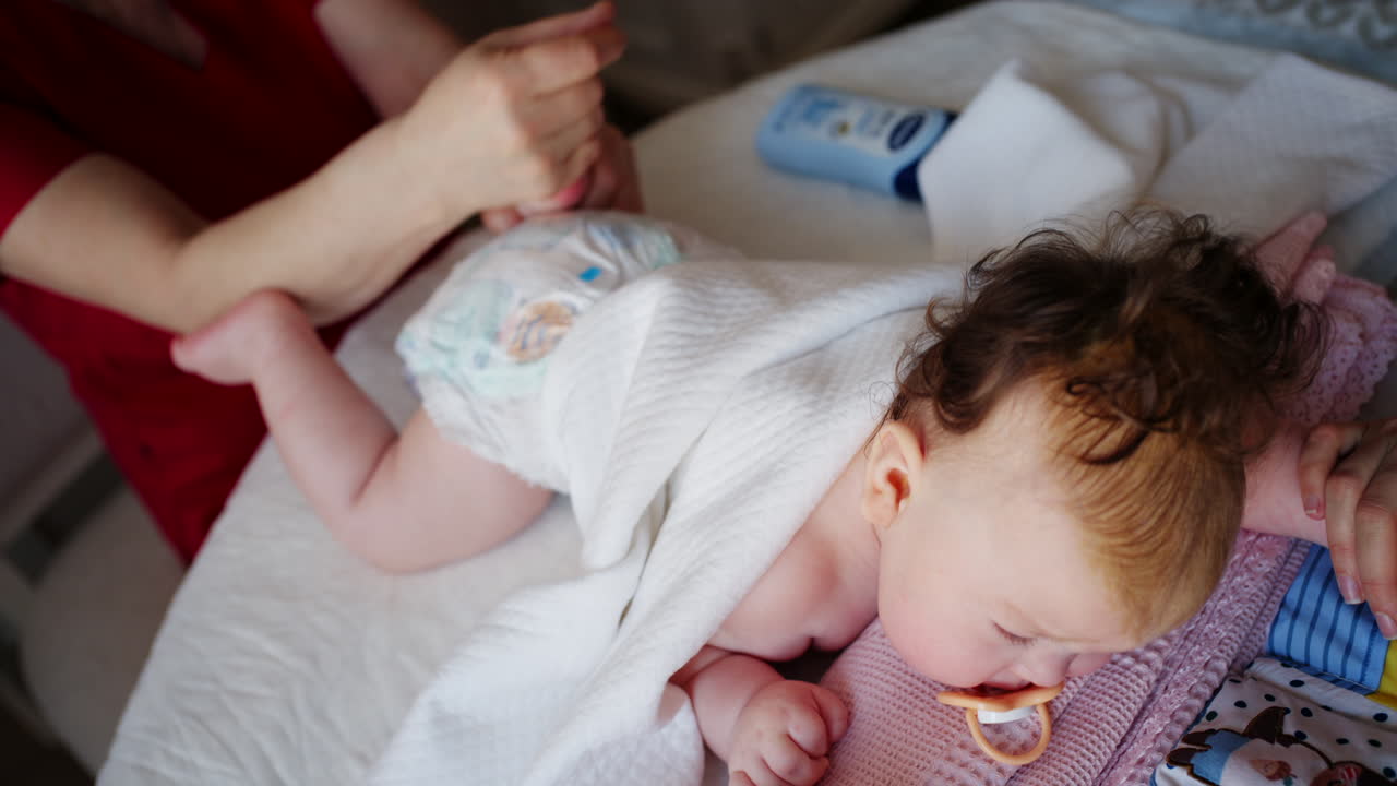 Bambino sdraiato sulla pancia mentre un adulto lo massaggia ed esegue esercizi di mobilità