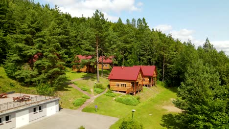 forest wooden cottages with red roofs for travelers accommodation in borucino, poland - drone shot