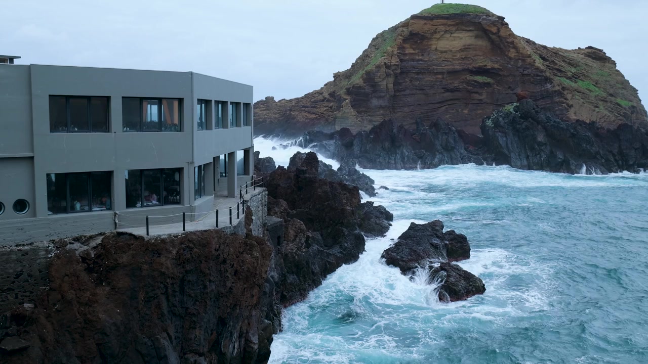 Edifício de Restaurante Moderno Empoleirado em uma Falésia Rochosa com Vista para Ondas Agitadas do Oceano