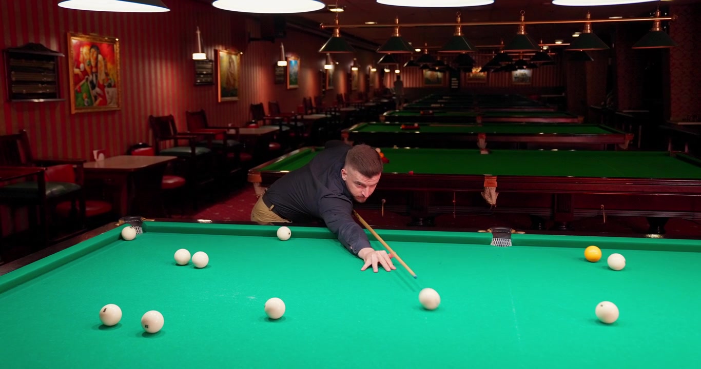 Man Concentrating While Playing Billiards in a Classic Pool Hall