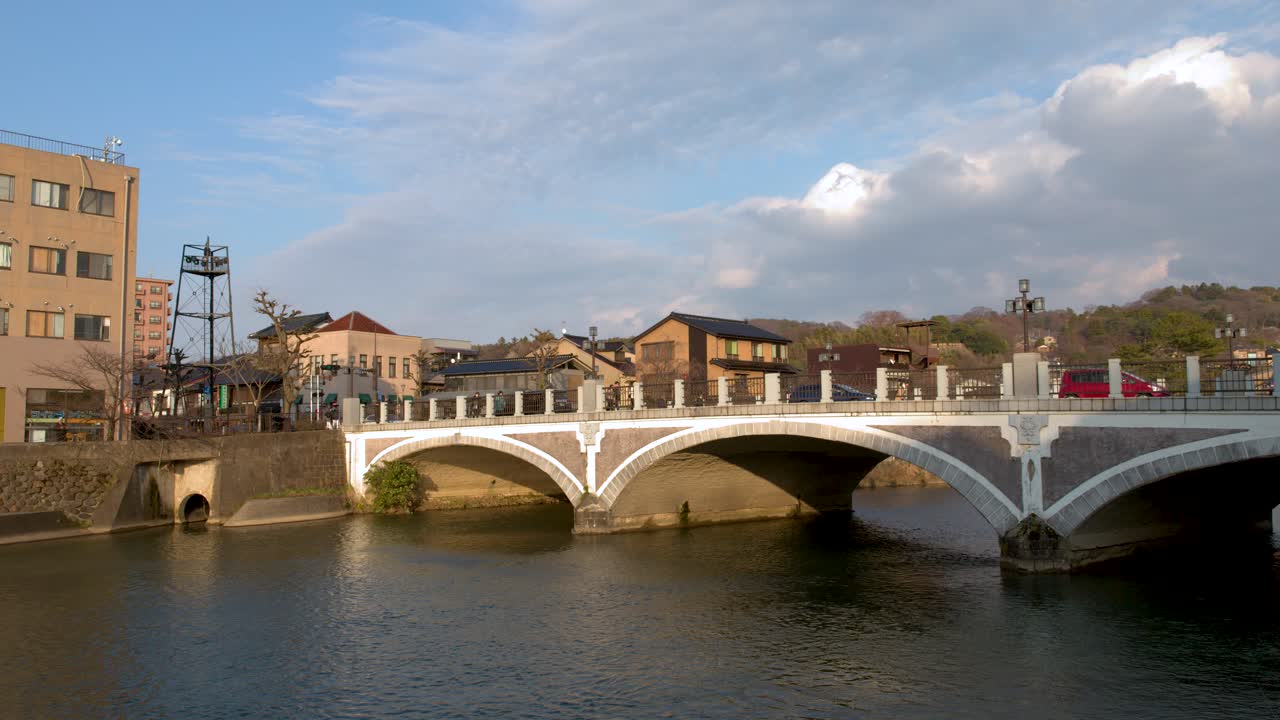 Panoramica statica ampia di un ponte in pietra a più arcate che attraversa il fiume Asano a Kanazawa.