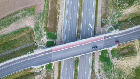 Toma-Aérea-De-Arriba-Hacia-Abajo-De-Los-Automóviles-Que-Circulan-Por-La-Carretera-Del-Puente-Sobre-Una-Autopista-Vacía-En-Una-Zona-Rural