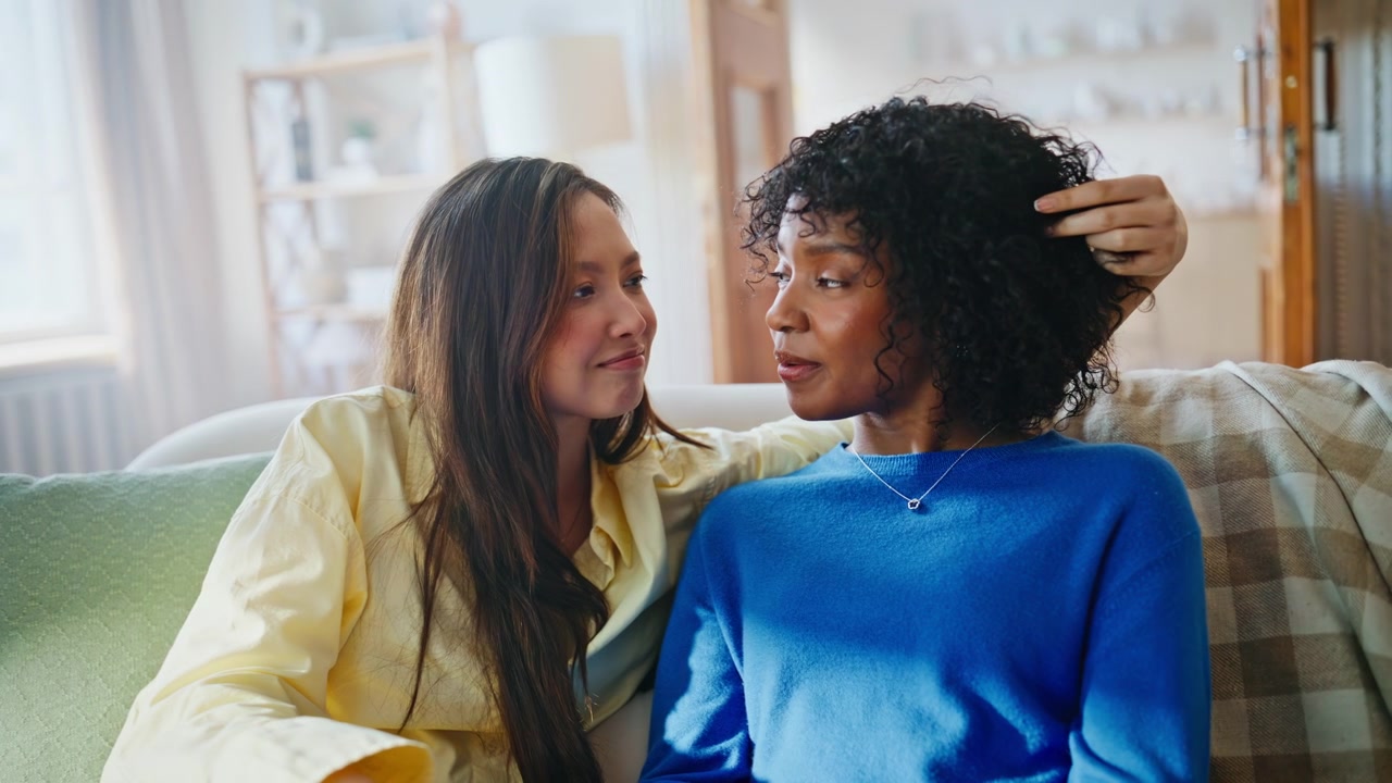 Pareja de mujeres multirracial abrazándose en el sofá. Mujer consolando a su novia en casa