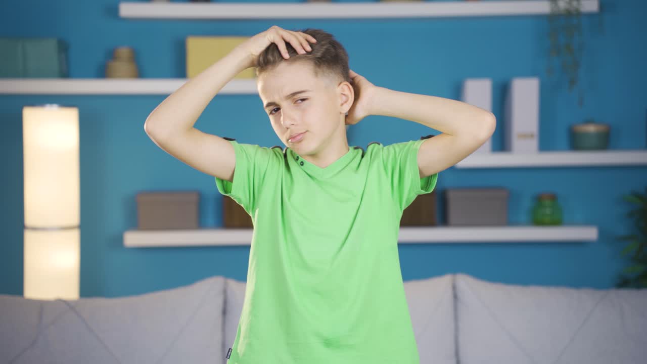 금발의 예쁜 소년이 머리카락으로 놀고 카메라를 쳐다보고 있습니다.