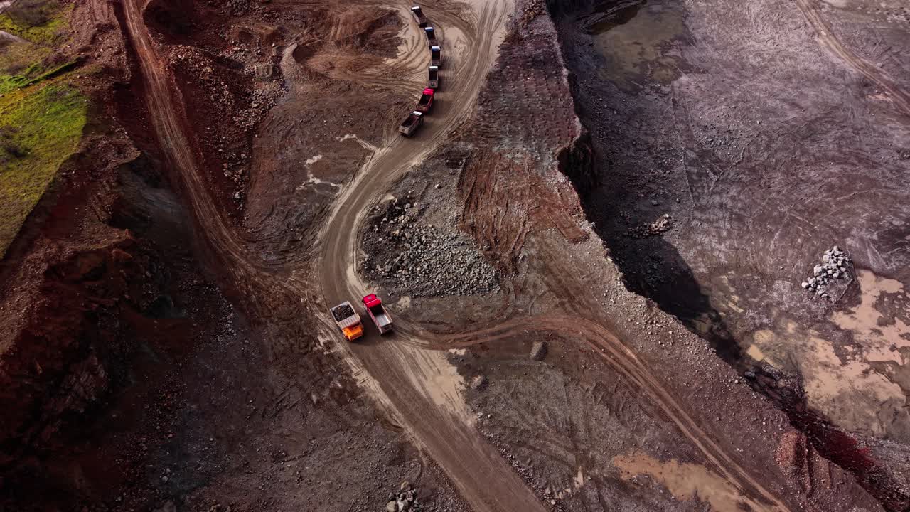 Trucks transport granite along a winding path in a quarry