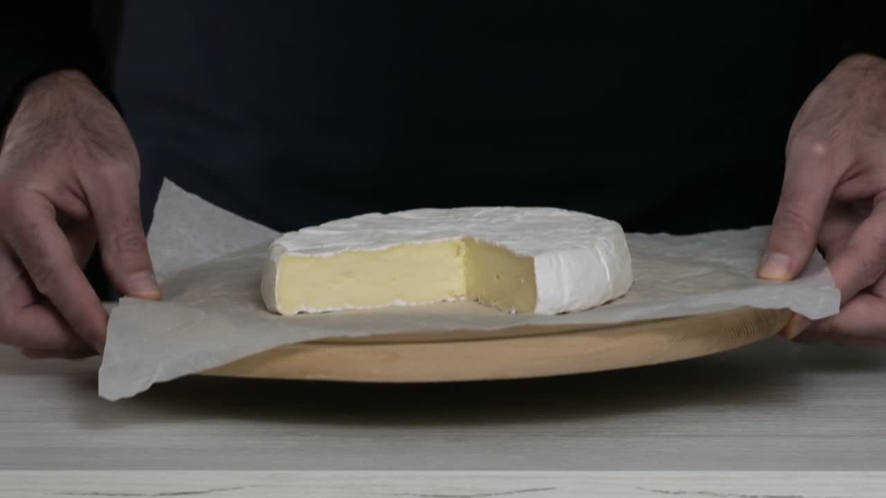 camembert queso crema de primer plano. el chef pone en la mesa con delicioso queso suave camembert. cabeza de queso de leche de cabra con moho blanco. cabeza redonda camembert cortado en pedazos. concepto de producto lácteo