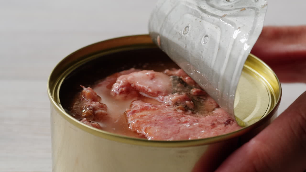 Smoked cod liver in oil in open tin can with fresh greens on wooden table. Seafoods delicacy. High quality 4k footage
