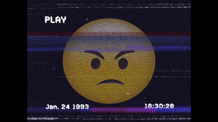 Digital animation of vhs glitch effect over angry face emoji against black background