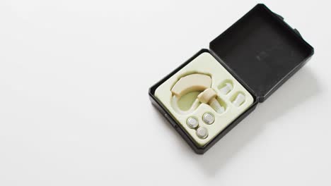 video of hearing aid and batteries in case, on white background with copy space