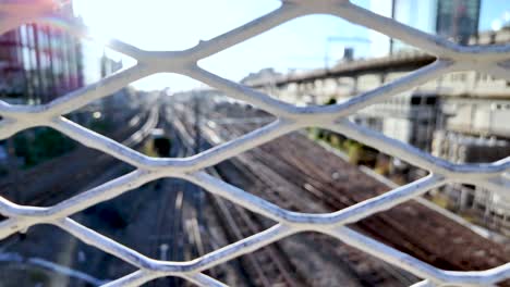 sun shining through an expanded metal mesh fence with osaka train lines in the background