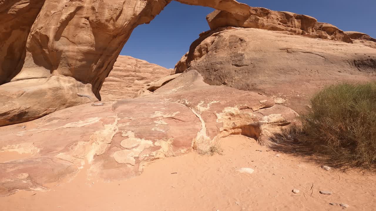 wadi rum, jordania, vista de ángulo bajo del arco de arenisca natural en un día caluroso y soleado, inclínate hacia arriba