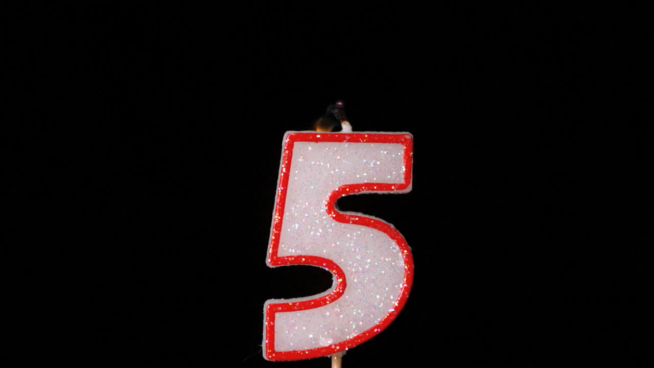 Cinque candele di compleanno che tremolano e si spengono su sfondo nero