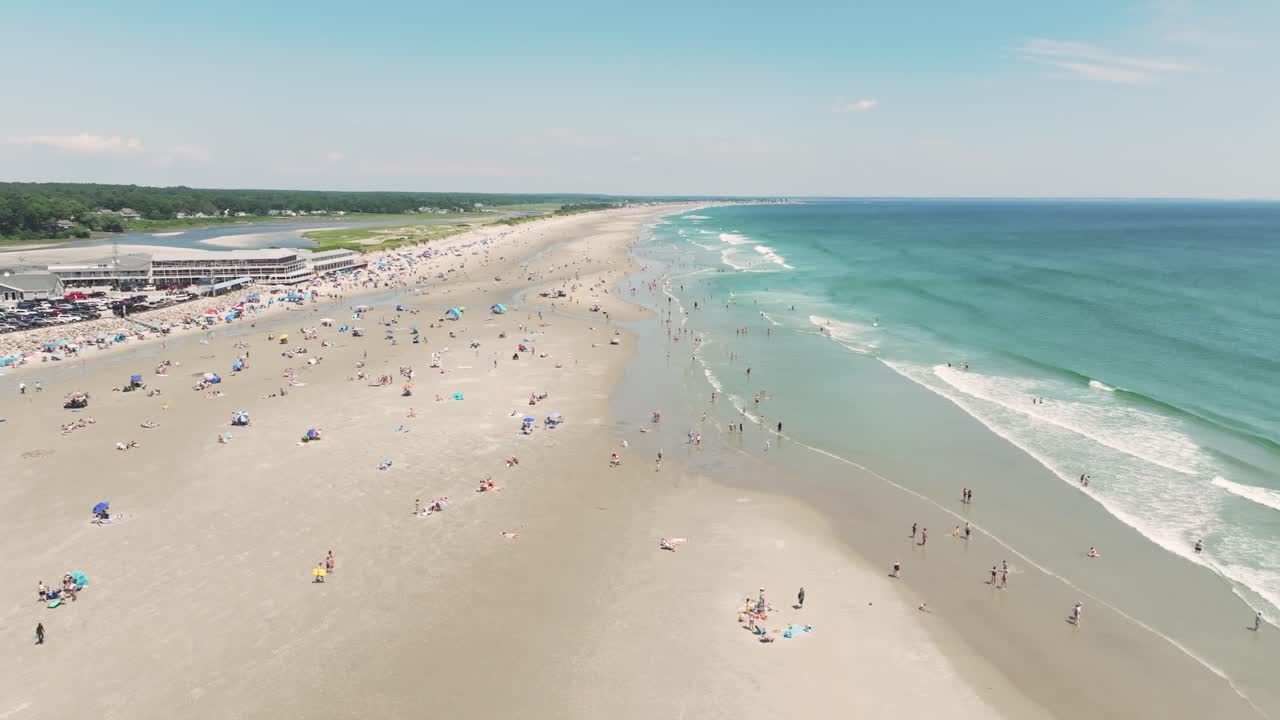 Aerial view of Ogunquit Beach, Maine on a sunny summer day. Families and beachgoers enjoy the expansive shoreline and clear blue Atlantic waters