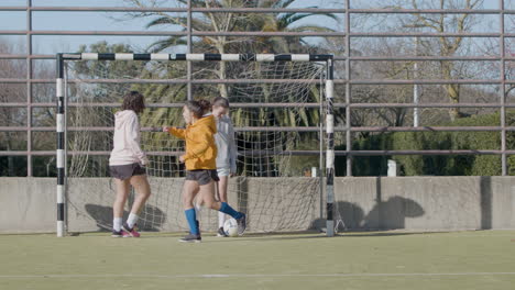 aktive teenager-mädchen, die im freien fußball spielen, und einer von ihnen punktet