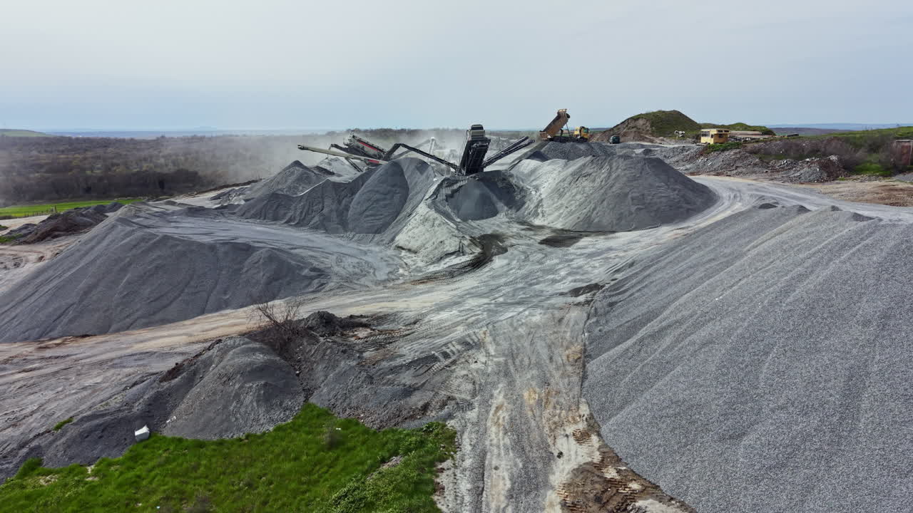 Operasi tambang granit dengan tumpukan batu besar dan mesin yang beroperasi di lingkungan luar ruangan.