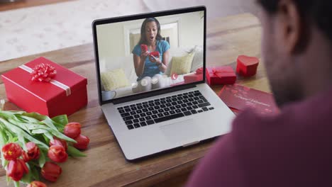 Fröhliche-Afroamerikanische-Frau,-Die-Ein-Geschenk-öffnet-Und-Einen-Videoanruf-Zum-Valentinstag-Auf-Dem-Laptop-Tätigt