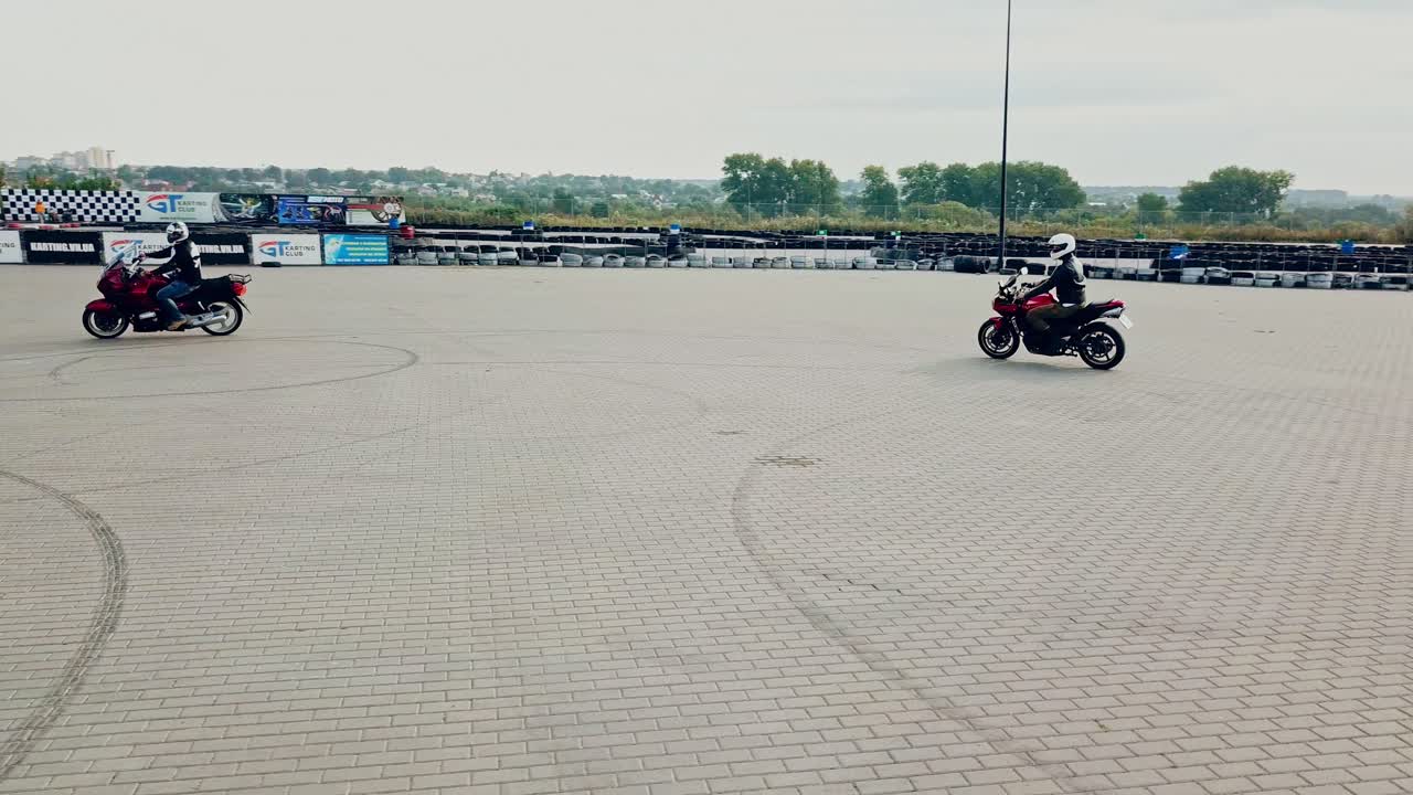 Two professional motobikers racing highspeed on a road in a circle way. Bikers on their motorcycles training riding on the background of city with modern buildings.
