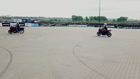 two professional motobikers racing highspeed on a road in a circle way. bikers on their motorcycles training riding on the background of city with modern buildings.