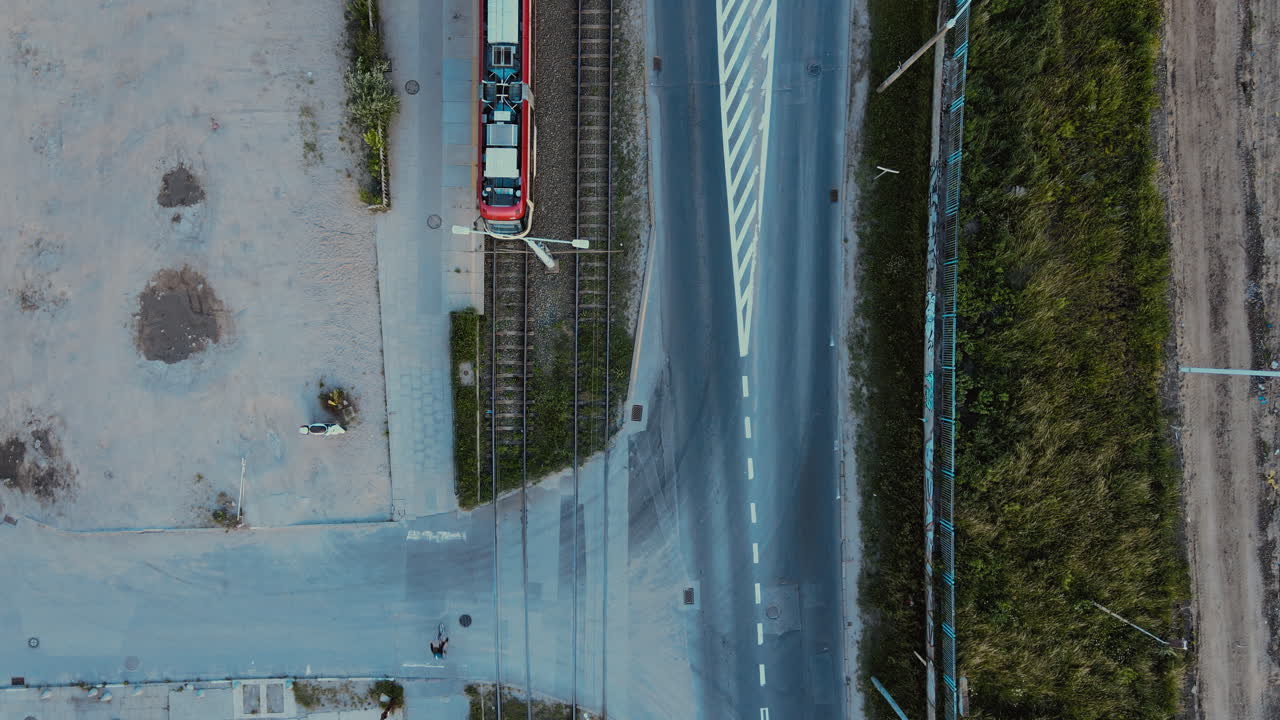 Aerial top down street in the city, tram leaves from the stop, single cars go down the street