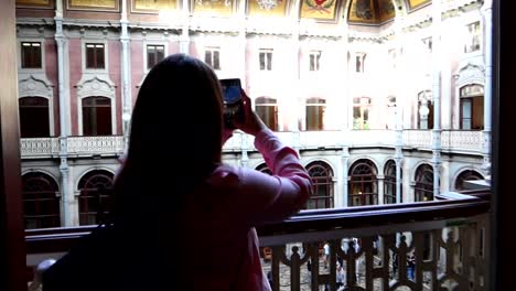 Mujer-En-Un-Balcón-Tomando-Una-Fotografía-Del-Patio-De-Las-Naciones-En-El-Palacio-Da-Bolsa,-Porto,-Portugal