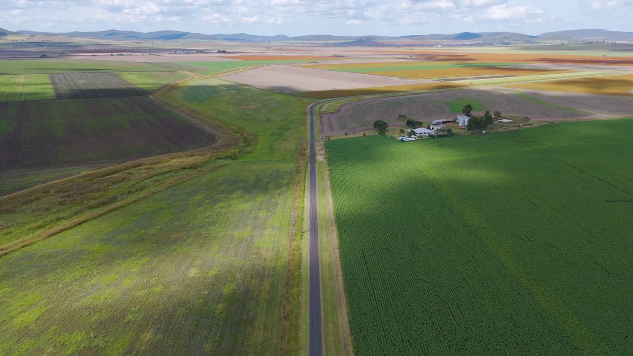 Drone flyover of cornfield, farmhouse, and road