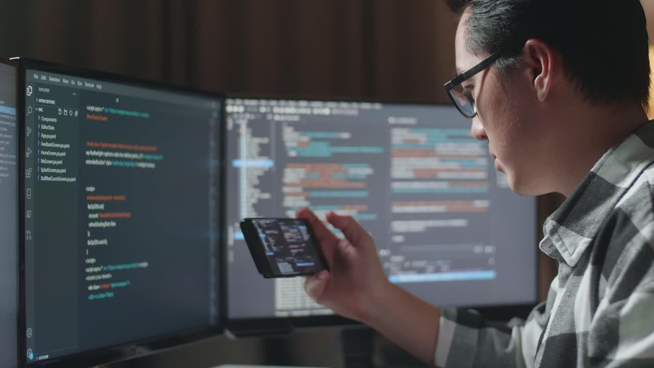 Programmer working late at night on computer and mobile phone
