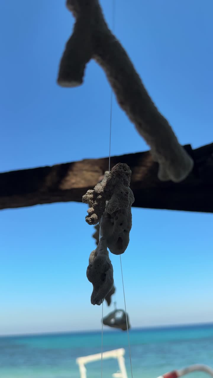 Decorazioni pendenti di corallo e conchiglie che ondeggiano su una spiaggia tropicale