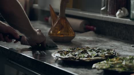 fabricante de pizza cortando perejil en la cocina