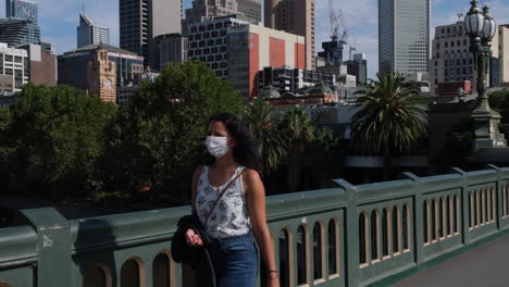 woman with mask walking over princes bridge during covid19 coronavirus