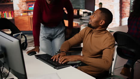 hombre con discapacidad escribiendo en la computadora y charlando con un compañero de trabajo