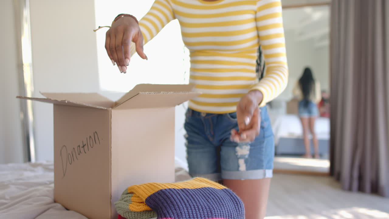 Packing clothes into donation box, woman organizing items in bedroom