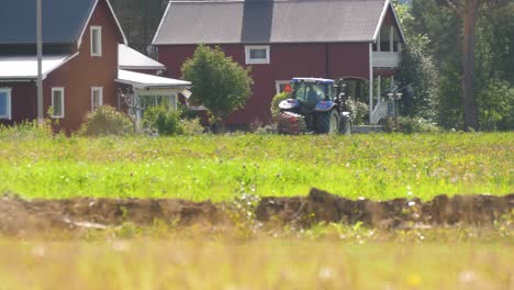 Medium-long-shot-of-tractor-leaving-the-field,-towards-the-village-in-rural-area