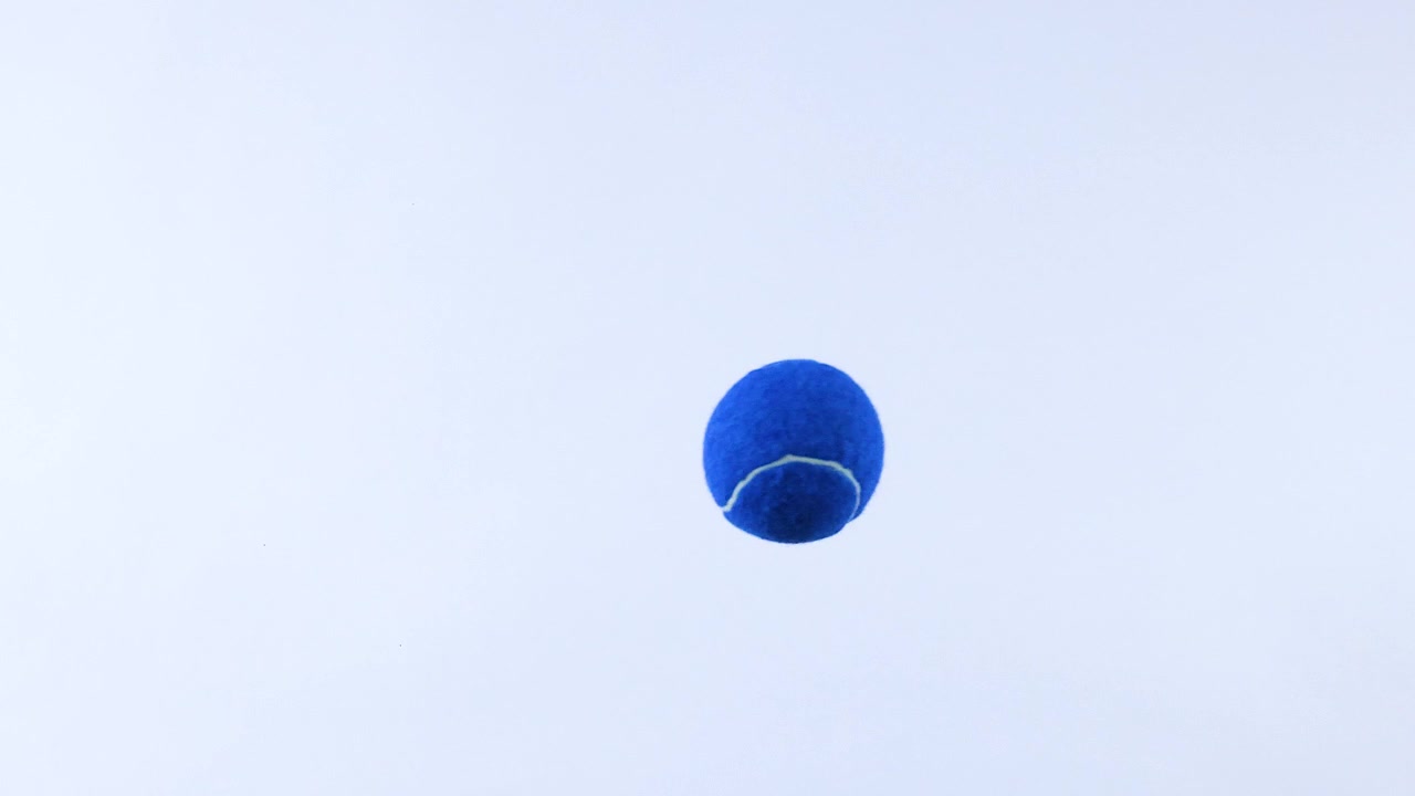 Bola tenis biru memantul di permukaan putih