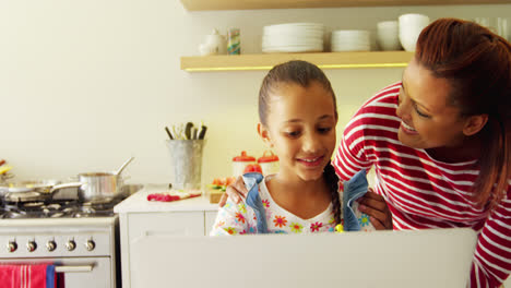 Mother-and-daughter-using-laptop-in-kitchen-worktop-4k