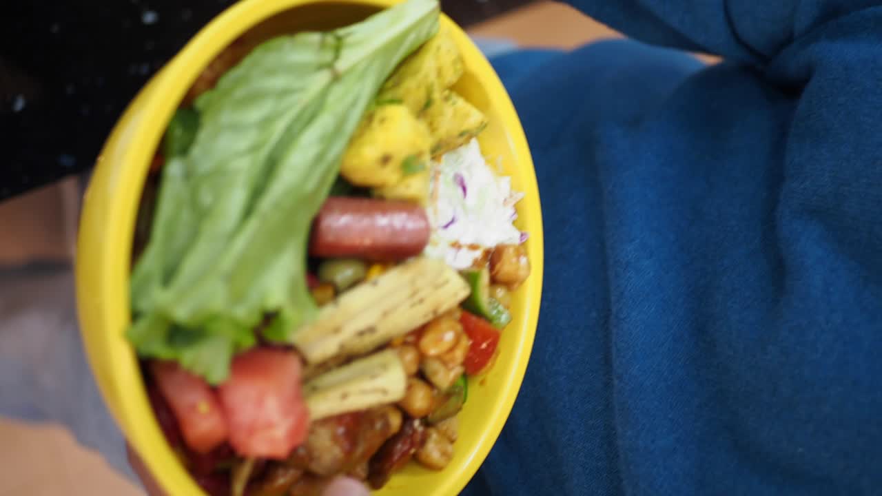 Person assembling a healthy salad bowl at a buffet
