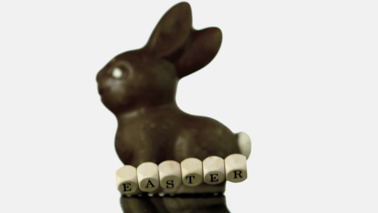 Lettere che formano la parola "Pasqua" che cadono davanti a un coniglio di cioccolato