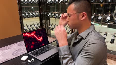 stressed asian millennial man looking at stock market crash on computer screen due to economic recession