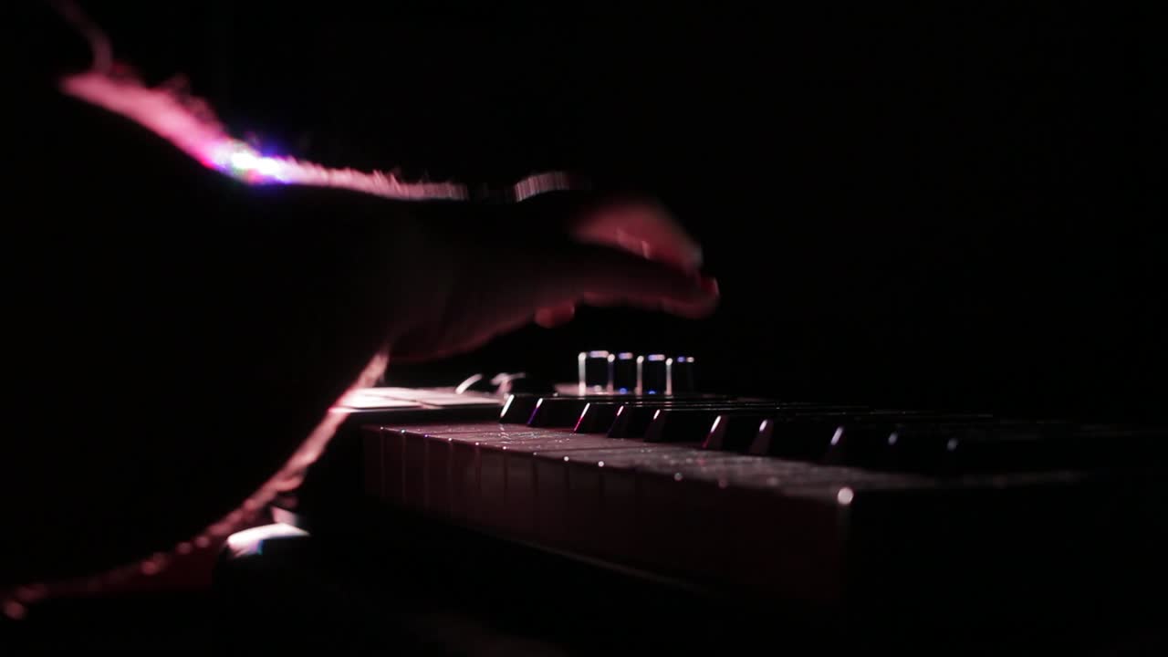 Close up male hands playing keyboard. DJ at light show concert.
