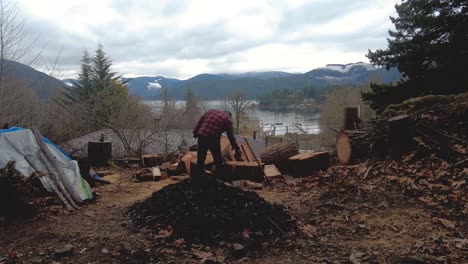 time lapse of man chopping firewood with lake, mountains and fast moving clouds