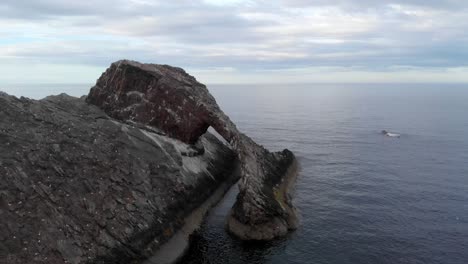 flying over bow fiddle rock - a natural sea arch - in the evening under the vibrant sky