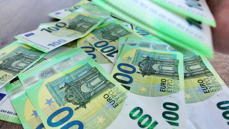 Ein Mann sammelt verstreute 100-Euro-Banknoten