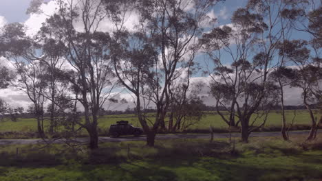 Side-on-follow-shot-of-vehicle-travelling-along-woodland-road