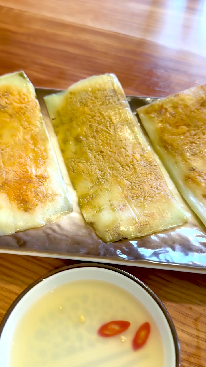 Primo piano ripreso a mano di torte di riso vietnamite banh nam servite con salsa di pesce al peperoncino.