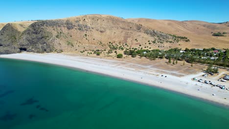drone shot moving backwards and curving around to reveal a campsite on rapid bay, a popular campsite in south australia