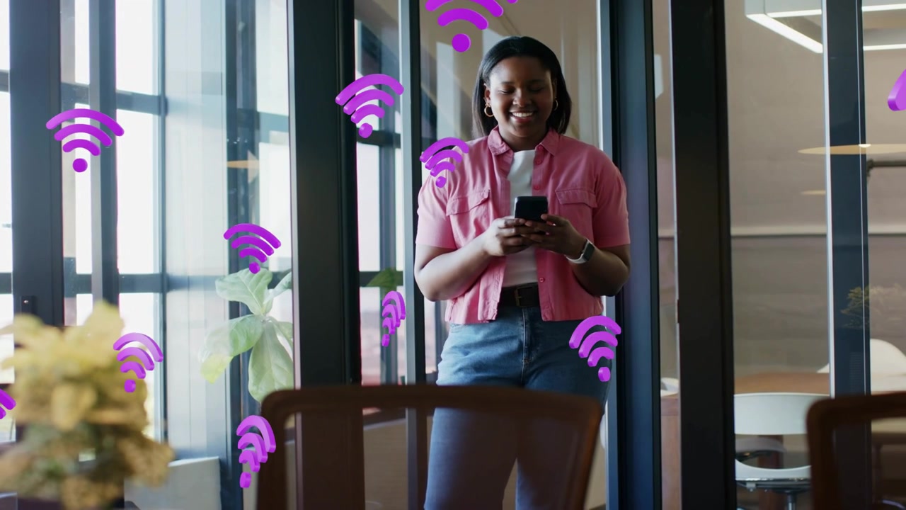 Kvinde tapper på telefon på kontor nær vinduer, lilla Wi-Fi-ikoner dukker op og formerer sig omkring hende