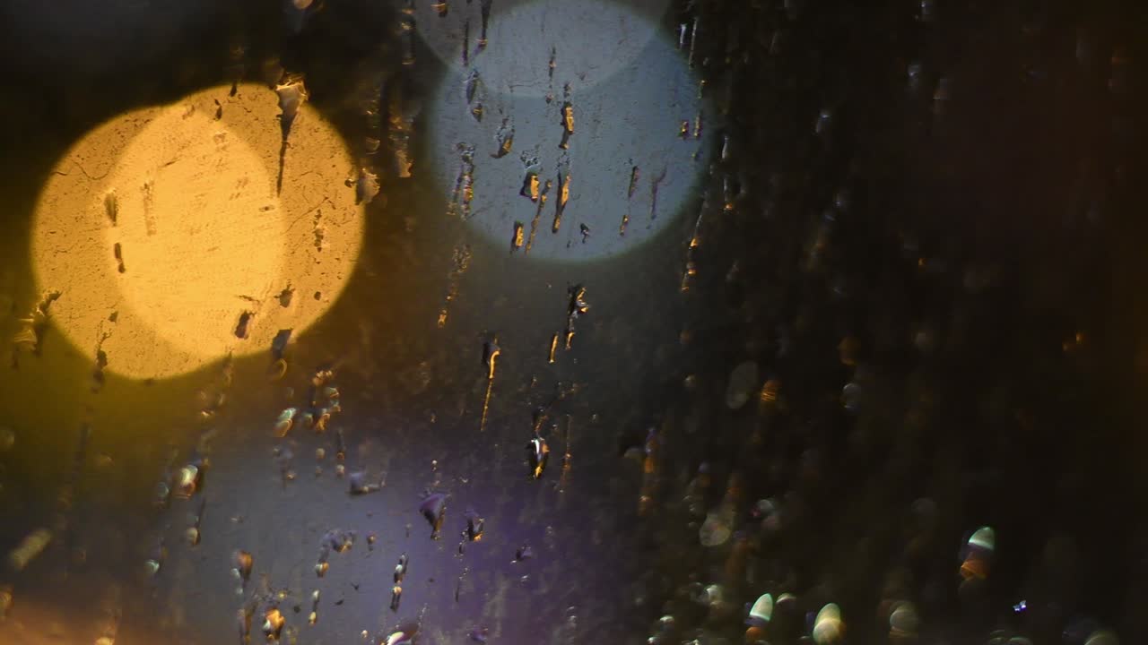 gotas de lluvia en la superficie de la ventana sucia con luces bokeh de fondo