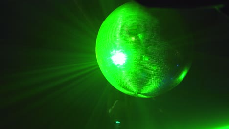 una gran bola de discoteca colgada del techo, girando con diferentes colores de iluminación reflejada en sus espejos