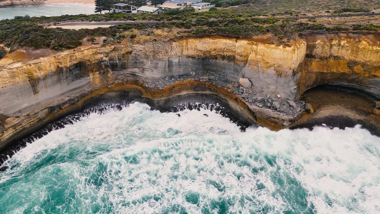 Drone captures dramatic waves crashing against the eroded cliffs of Port Campbell, Australia, highlighting natural beauty and geological formations
