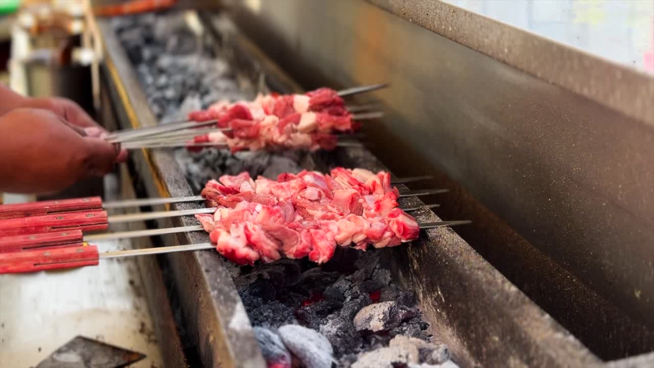 A shot of an outdoor barbecue in Altay, Central Asia, cooks grill traditional Muslim street food. They skillfully flip skewers of lamb, sending plumes of aromatic smoke rising from the hot charcoal