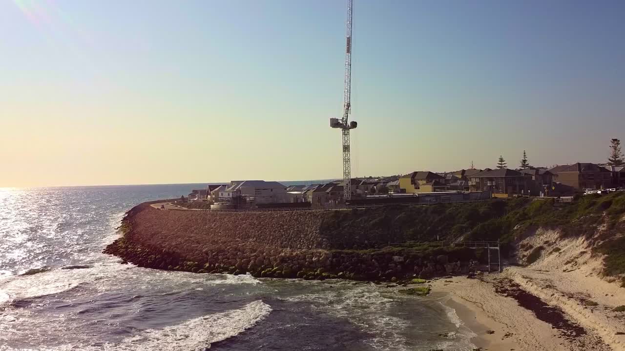 Claytons Beach in Mindarie, Australia, with sandy shores, ocean waves, and a coastal tower view